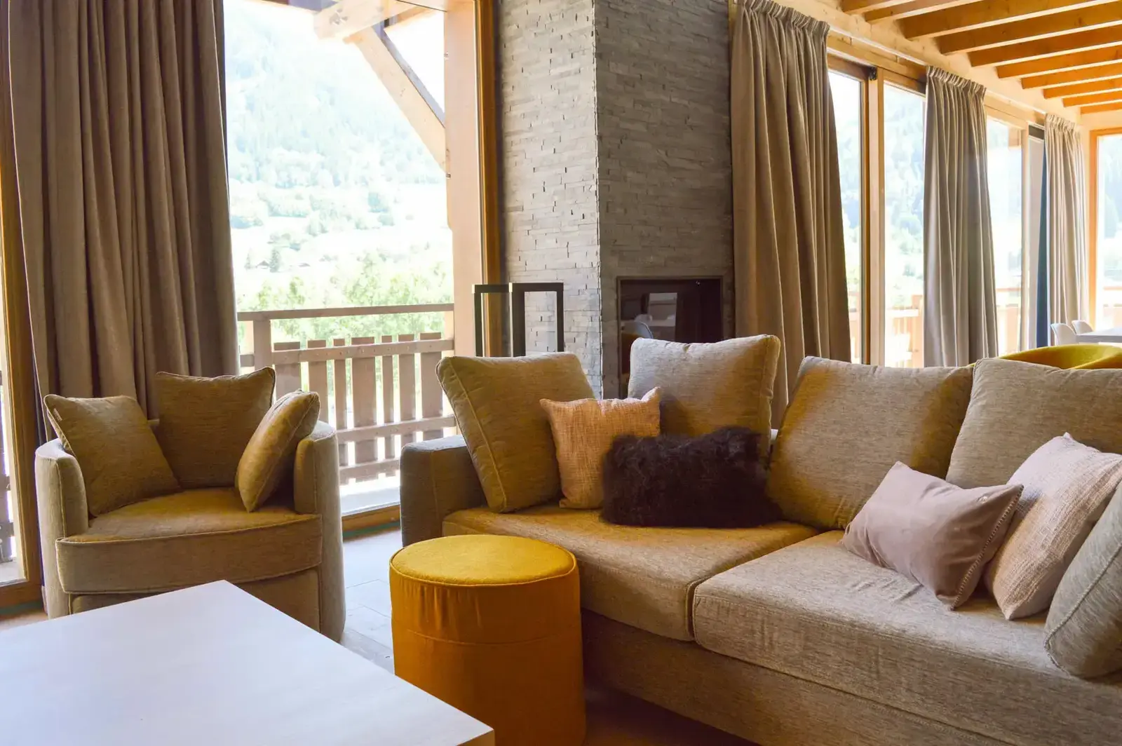 Chalet living room: sofa, armchairs and fireplace in front of large windows