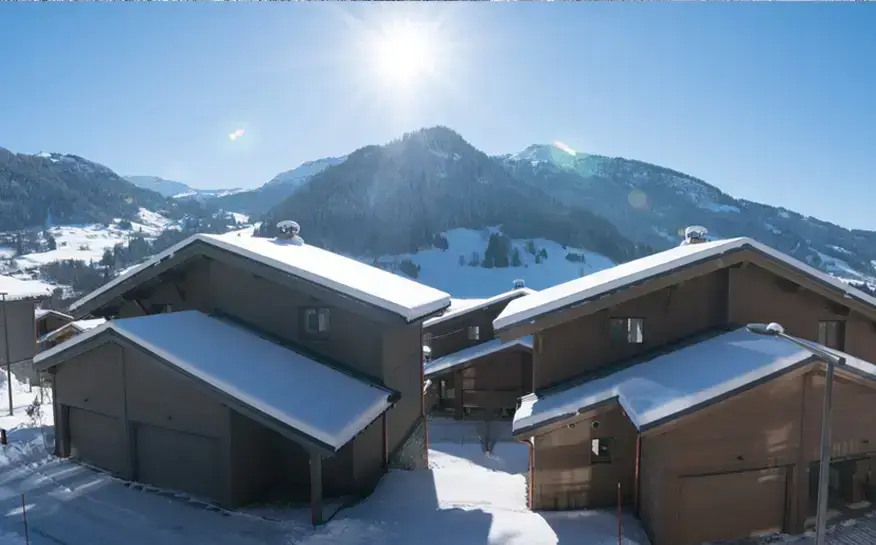 Chalets of the hamlet in the snow, facing the mountains